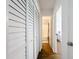 Bright hallway with hardwood floors features white shuttered closet doors and leads to the bathroom and a bedroom at 11447 Park Blvd # 205, Seminole, FL 33772