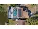 Aerial view of a home with a screened pool, solar panels, and a deck overlooking the water at 12416 Queensland Ln, Tampa, FL 33625