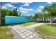 View of the backyard showing stone pavers, lush green lawn, landscaping, and the property's blue siding at 13325 1St E St, Madeira Beach, FL 33708