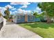Charming single-story home with a blue exterior, well-manicured lawn, and a decorative orange front door at 13325 1St E St, Madeira Beach, FL 33708