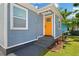 Close-up of a charming home's entrance featuring a decorative orange front door and freshly landscaped yard at 13325 1St E St, Madeira Beach, FL 33708