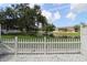 View of a tranquil backyard with a pond, fountain, and well-maintained grass beyond a white picket fence at 13755 Orange Sunset Dr # 101, Tampa, FL 33618