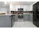 Updated kitchen showcasing stainless steel appliances, gray lower cabinets, and bright white upper cabinets at 13800 Judy Ave, Hudson, FL 34667