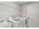 Bright laundry room with washer, dryer, utility sink and wire rack shelf at 14266 Creek Run Dr, Riverview, FL 33579