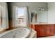 Bathroom featuring a soaking tub, cherry cabinetry, and a large window overlooking neighborhood at 1531 Ember Ln, Tarpon Springs, FL 34689