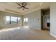 Large carpeted main bedroom with a ceiling fan, tray ceiling, and ensuite bathroom and balcony access at 1531 Ember Ln, Tarpon Springs, FL 34689