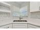 Close-up of the kitchen sink that features light-colored cabinetry, countertops, and backsplash at 1701 62Nd S Ter, St Petersburg, FL 33712