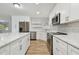 A modern, bright kitchen features stainless steel appliances, white cabinets, and an island with stone countertops at 1701 62Nd S Ter, St Petersburg, FL 33712