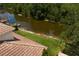 Aerial view of riverfront home with red-tiled roof, lush grass, and kayak on the water at 18050 Cozumel Isle Dr, Tampa, FL 33647