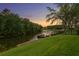 Picturesque backyard view featuring a private dock on the water, surrounded by lush greenery and mature trees at sunset at 18050 Cozumel Isle Dr, Tampa, FL 33647