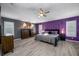 A large bedroom with ceiling fan, unique purple accent wall, and wood-look flooring at 19309 Garden Quilt Cir, Lutz, FL 33558