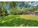 Lush backyard with mature trees and a screened-in pool area, offering a serene outdoor space at 2011 Water Wheel Ct, Dunedin, FL 34698