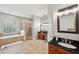 Elegant bathroom featuring dual vanities, a glass block window, soaking tub, and walk-in shower at 2011 Water Wheel Ct, Dunedin, FL 34698