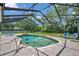A beautiful screened-in pool with a spa, surrounded by a brick patio and lush greenery at 2011 Water Wheel Ct, Dunedin, FL 34698