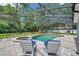Relaxing screened pool area with lounge chairs, offering a private and serene outdoor retreat surrounded by lush greenery at 2011 Water Wheel Ct, Dunedin, FL 34698