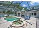 Enclosed pool and spa with patio furniture, complemented by lush landscaping and inviting outdoor spaces at 2011 Water Wheel Ct, Dunedin, FL 34698
