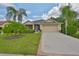 Inviting single-Gathering home features a lush front lawn, palm trees, and a screened-in porch for relaxing outdoors at 2128 Worthington Greens Dr, Sun City Center, FL 33573