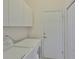 Well-lit laundry room with washer, dryer, and ample white cabinet storage space at 2128 Worthington Greens Dr, Sun City Center, FL 33573