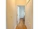 Hallway with laminate floors, leading to a bathroom with white wooden door, also features a closet with bi-fold doors at 2130 Broadway View Ave, Brandon, FL 33510
