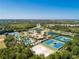 Extensive aerial view showcasing community amenities, including pools, tennis courts, and sand volleyball, nestled in greenery at 2424 Caraway Dr, Venice, FL 34292