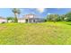 Expansive backyard featuring a screened-in pool area with palm trees and ample green space at 2424 Caraway Dr, Venice, FL 34292