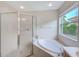 Bright bathroom featuring a garden tub, glass shower, window, and neutral tile at 2424 Caraway Dr, Venice, FL 34292