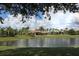 Scenic view of the community clubhouse by a tranquil pond, complemented by well-manicured lawns and palm trees at 2424 Caraway Dr, Venice, FL 34292