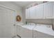 Efficient laundry room equipped with appliances, storage cabinets, and a utility sink at 2424 Caraway Dr, Venice, FL 34292