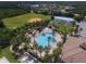 Aerial view of a sparkling pool and recreational area surrounded by palm trees, sports courts, and green space at 2424 Caraway Dr, Venice, FL 34292