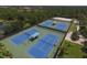 Aerial view of the community's well-maintained blue tennis courts and lush landscaping at 2424 Caraway Dr, Venice, FL 34292