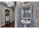 Well-lit half-bathroom with a pedestal sink, decorative mirror, and modern lighting at 2435 Edgewater Falls Dr, Brandon, FL 33511