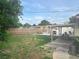 Fenced backyard with grass and partial patio and partial covered patio area, BBQ grill, and lush trees at 2444 35Th N St, St Petersburg, FL 33713