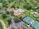 Aerial view of the community clubhouse, pool, tennis courts, and manicured green spaces in a beautifully maintained community at 2608 Camille Dr, Palm Harbor, FL 34684