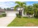 Charming two-story home with lush landscaping, palm trees, and a well-maintained lawn creating a welcoming curb appeal at 27353 Edenfield Dr, Wesley Chapel, FL 33544