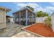 Backyard with paver patio, screened-in lanai, flower bed, and white fencing at 3145 Domino Dr, Holiday, FL 34691
