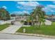 Aerial view of the front exterior of a home featuring a garage, palm trees, landscaping and green lawn at 3145 Domino Dr, Holiday, FL 34691