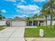 Charming single-story home featuring a well-manicured lawn, palm trees, and a two-car garage at 3145 Domino Dr, Holiday, FL 34691