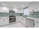 Renovated kitchen featuring white cabinets, stainless appliances, modern countertops and decorative backsplash at 3145 Domino Dr, Holiday, FL 34691