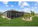 Lush backyard featuring a screened lanai, a garden with accent boulders, and manicured green grass at 31921 Magna Gulf Loop, San Antonio, FL 33576
