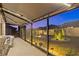 Twilight view of the home's rear exterior, showcasing the screened lanai and landscaped yard with illuminated landscaping at 31921 Magna Gulf Loop, San Antonio, FL 33576
