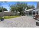 Spacious backyard patio with outdoor seating and a lush lawn leading to the screened pool at 403 Carriage House Ln, Tarpon Springs, FL 34688
