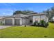 Charming single-story home with a gray roof, manicured lawn and landscaping, and neutral tones at 403 Carriage House Ln, Tarpon Springs, FL 34688