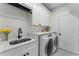 Well-lit laundry room featuring a sink, modern appliances, and storage cabinets at 403 Carriage House Ln, Tarpon Springs, FL 34688