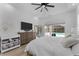 Well-lit main bedroom with ceiling fan, dresser, TV, and sliding glass doors to pool at 403 Carriage House Ln, Tarpon Springs, FL 34688