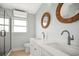 Bright bathroom featuring double sinks, modern faucets and mirrors, walk-in shower with glass doors at 403 Normandy Rd, Madeira Beach, FL 33708