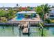 Waterfront home featuring a private dock and boat lift along a tranquil canal with a refreshing pool and vibrant landscaping at 403 Normandy Rd, Madeira Beach, FL 33708