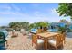 Inviting waterfront patio with stylish furniture, dining area, grill, and lush tropical landscaping around the pool at 403 Normandy Rd, Madeira Beach, FL 33708