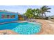 Inviting pool surrounded by a brick-paved patio with a bar, lush trees, and blue waterfront home at 403 Normandy Rd, Madeira Beach, FL 33708