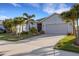 Inviting single-story home with a long driveway, two-car garage, and meticulously maintained landscaping with palm trees at 6211 114Th E Dr, Parrish, FL 34219