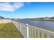Picturesque view of the pond from the backyard, framed by a white fence and lush green lawn at 6211 114Th E Dr, Parrish, FL 34219